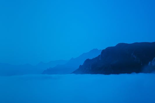 Nuances de bleu, trois montagnes sur une mer de nuages et un bleu profond